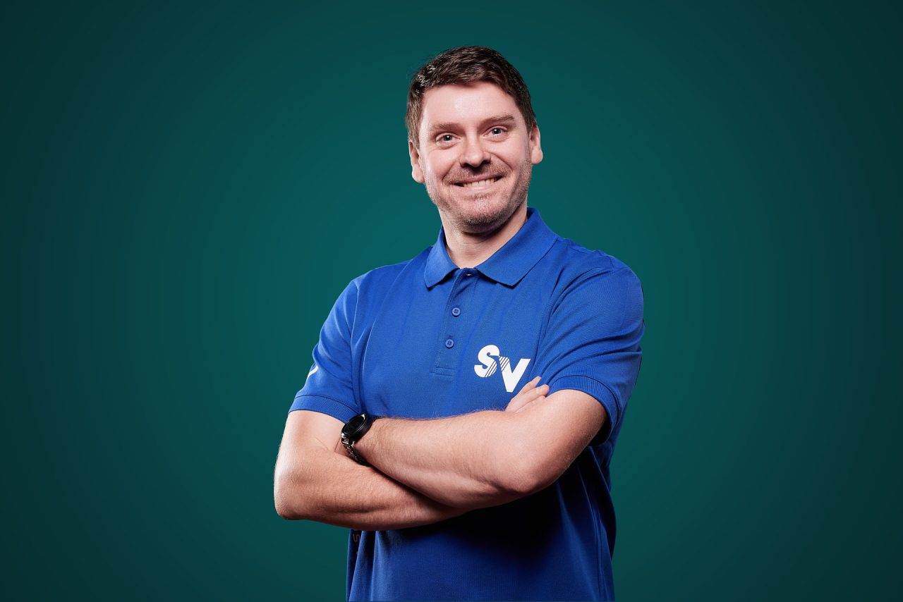 Mitarbeiter Alexander freundlich lächelnd in blauem Spandauer Velours Shirt